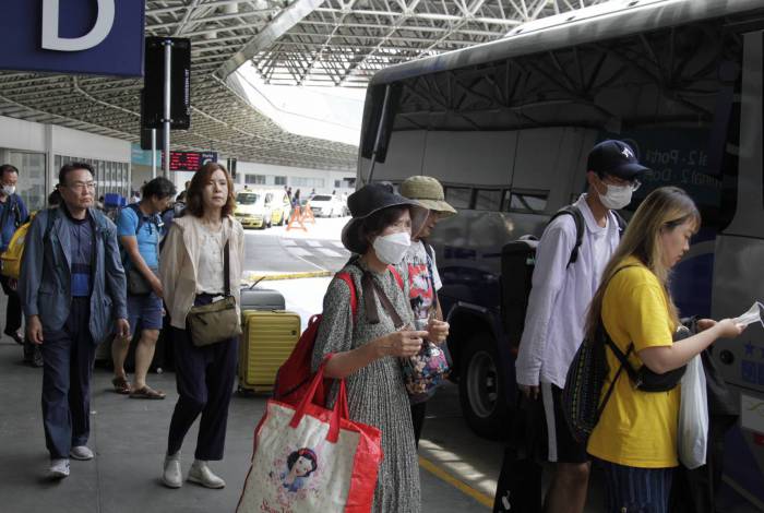 Dezenas de turistas orientais desembarcam no Aeroporto do Galeão, na Ilha do Governador, com o uso de máscaras protetoras