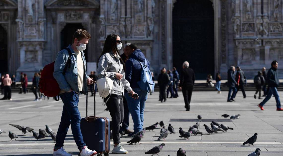 Turistas usando máscaras caminham na Piazza del Duomo, no centro de Milão - AFP