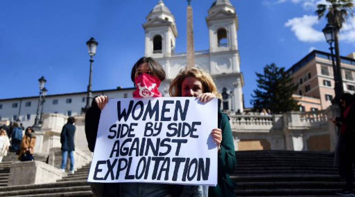 Mulheres seguram um cartaz durante flash mob do Dia Internacional da Mulher, na Piazza di Spagna, em Roma (Photo by Tiziana FABI / AFP)