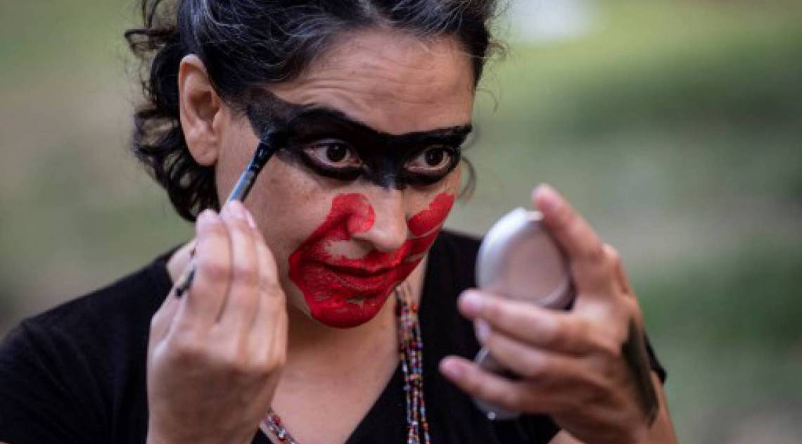 Mulher pinta o rosto para protestos pelo Dia Internacional da Mulher, em Santiago (Photo by Martin BERNETTI / AFP)