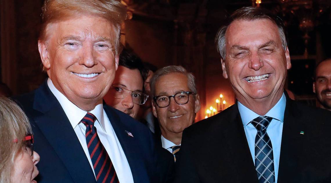 Handout picture released by the Brazilian Presidency on March 12, 2020 showing US President Donald Trump (L), Brazilian President Jair Bolsonaro (R) and his press advisor Fabio Wajngarten (2-L, behind Trump) during a dinner in Mar a Lago, Florida, United States, on March 7, 2020. - Brazilian President Jair Bolsonaro's communications chief, Fabio Wajngarten, who met US President Donald Trump last weekend at his Florida resort, has tested positive for the new coronavirus, the government said on March 12, 2020. Wajngarten, chief spokesman for the Brazilian government, travelled with Bolsonaro last Saturday to Tuesday to the United States. ALAN SANTOS/BRAZILIAN PRESIDENCY/AFP