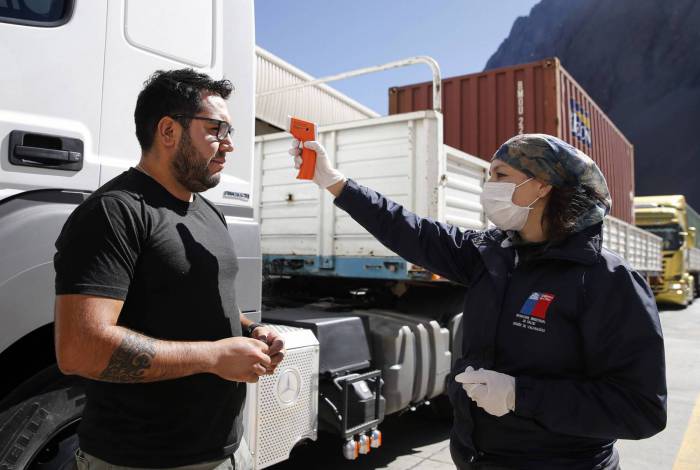 Um oficial controla a temperatura de um motorista de caminhão no Paso Internacional Los Libertadores, nos Andes, Chile