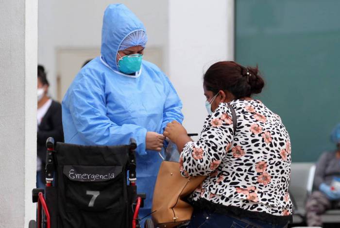 Um profissional de saúde ajuda uma mulher na sala de emergência de um hospital em Guayaquil, Equador, em 1º de abril