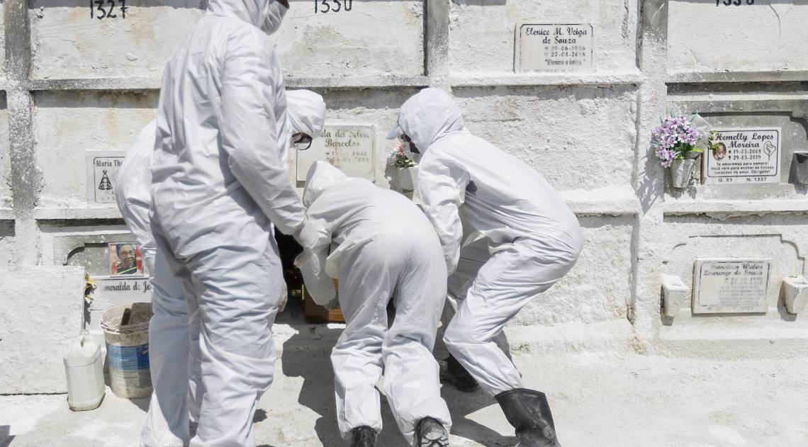 Rio - 01/04/2020 - COVID 19 - CORONAVÍRUS - Cemitério Sao Joao Batista - Enterro de Magna Soares Almeida, vitima do Coronavírus, Covid-19. Viuvo e familiares velam o corpo em um local aberto, caixão sempre fechado e depois acompanham o  caixão ate o sepultamento.  Os coveiros tiveram que mudar a vestimenta, as luvas simples e uniformes comuns deram lugar a trajes especiais. Macacão descartável, botas, luvas, óculos e uma máscara para enterrarem pessoas com suspeitas ou casos confirmados da Covid-19. Foto: Daniel Castelo Branco / Agencia O Dia