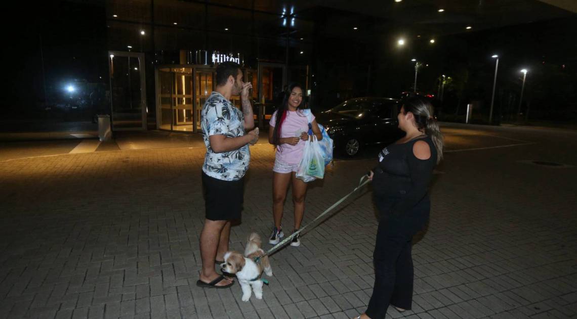 Flay chega ao hotel de máscara e posa com fãs