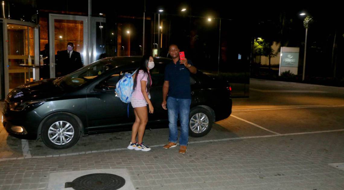 Flay chega ao hotel de máscara e posa com fãs
