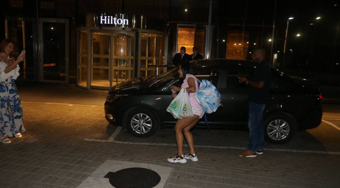 Flay chega ao hotel de máscara e posa com fãs