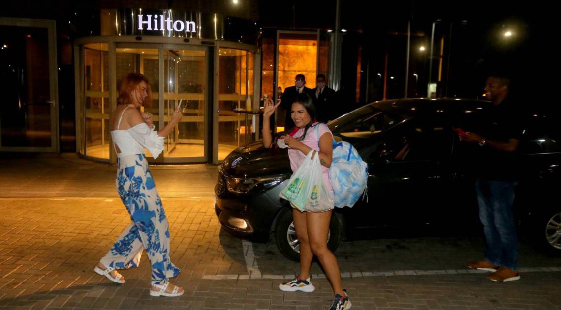 Flay chega ao hotel de máscara e posa com fãs