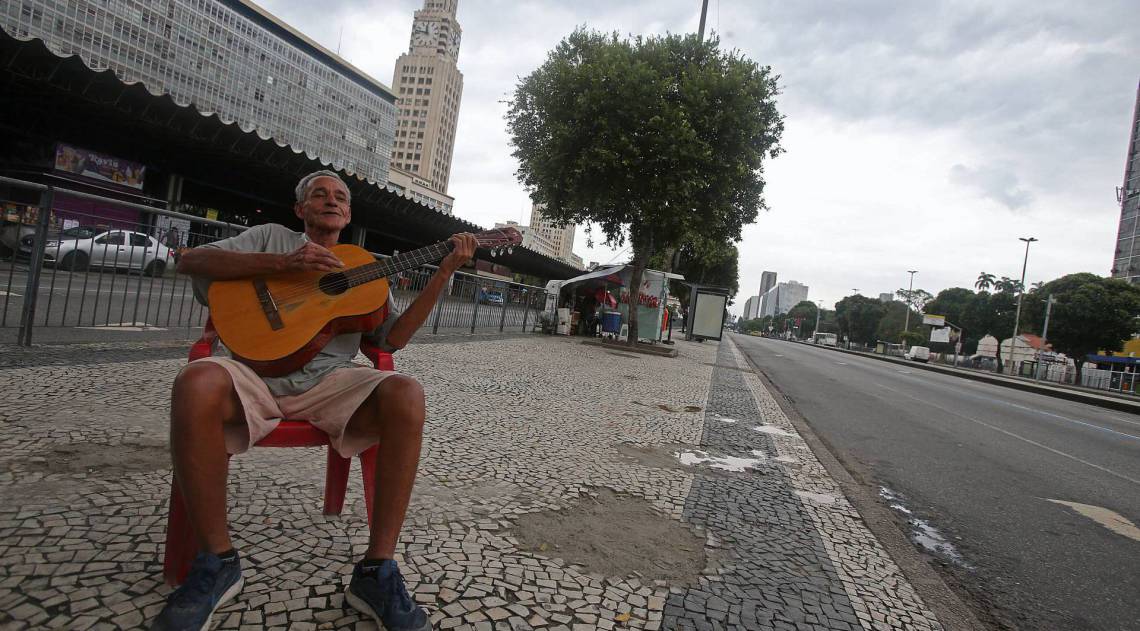Rio - 09/04/2020 - COVID 19 - CORONAVÍRUS - Movimentação de pessoas e veículos na Av. Presidente Vargas, no Centro do Rio. Em época de quarentena, muitas pessoas pelas ruas.Na foto o vendedor ambulante; Edimilson Ferreira de Freitas, 63 anos, morador do Morro da Providencia, reclama muito que o movimento de vendas da sua barraquinha caiu muito. Enquanto isso ele fica tocando seu violão para distrair. a.  Foto: Daniel Castelo Branco / Agencia O Dia