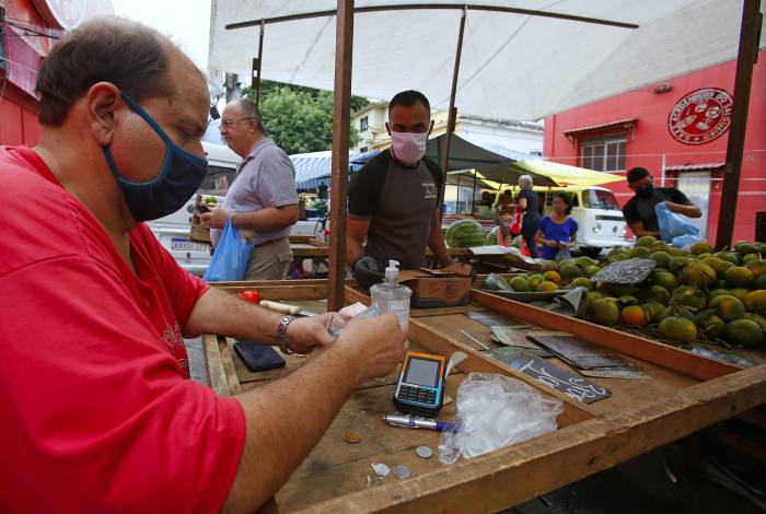 O feirante Silvio de Almeida: álcool em gel para reduzir riscos de contágio na barraca de frutas 
