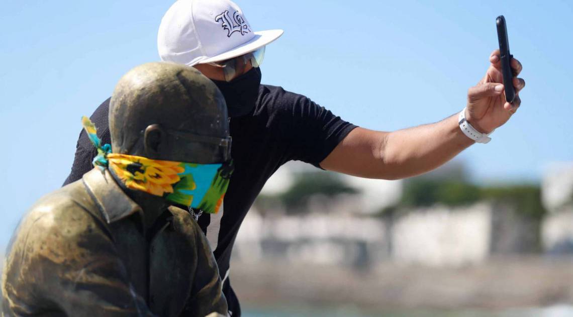 Rio, 23/04/2020  - COVID 19 - CORONAVIRUS - Estatuas em diversos pontos da cidade com mascara no rosto, na foto Lennon faz uma foto ao lado de Carlos Drumond, coronavirusrio. Foto: Gilvan de Souza /Agencia O Dia