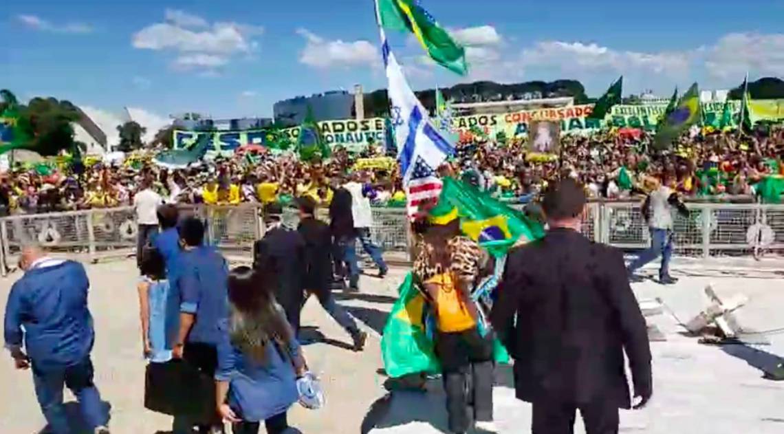 Durante manifestação, Um dos acompanhantes do presidente empunha um mastro com as bandeiras dos Estados Unidos, de Israel e do Brasil
