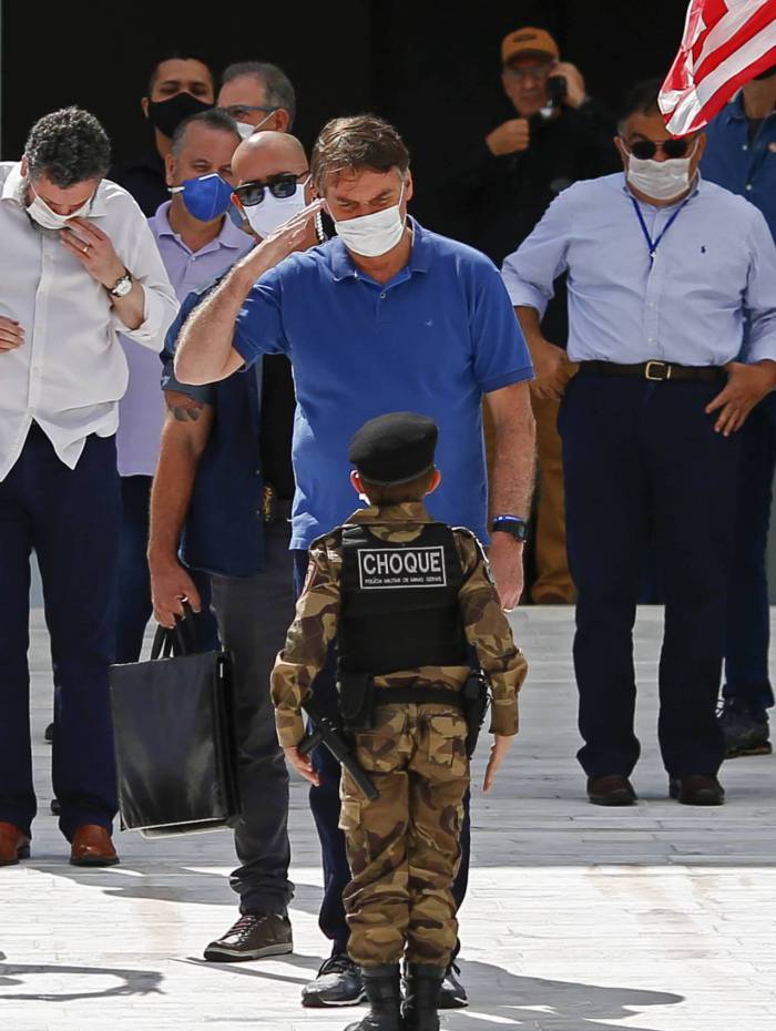 Brazilian President Jair Bolsonaro (C) salutes a child in a military costume during a rally in Brasilia on May 17, 2020, amid the novel coronavirus pandemic. - Brazil's COVID-19 death toll passed 15,000 on Saturday, official data showed, while its number of infections topped 230,000, making it the country with the fourth-highest number of cases in the world. (Photo by Sergio LIMA / AFP)
      Caption