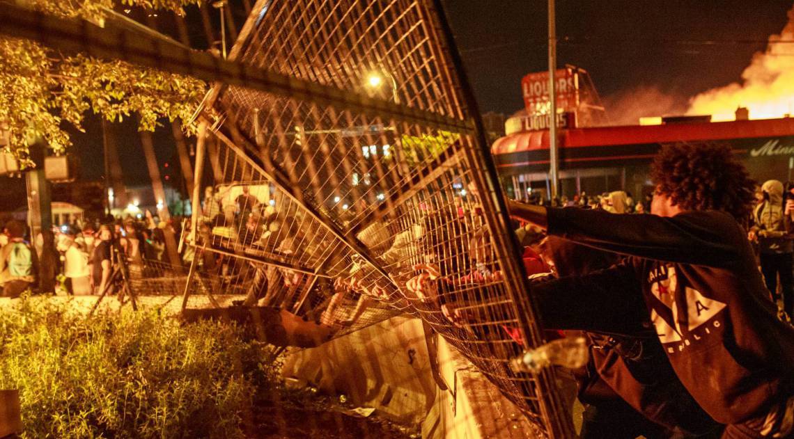 Manifestantes abrem um portão do lado de fora da delegacia de polícia 