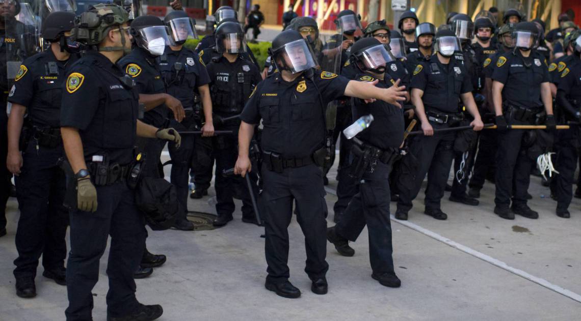 Policiais esquivam-se de garrafas de &aacute;gua ap&oacute;s uma marcha pac&iacute;fica contra a morte de George Floyd, no centro de Houston, Texas, na ter&ccedil;a-feira, 2 de junho de 2020