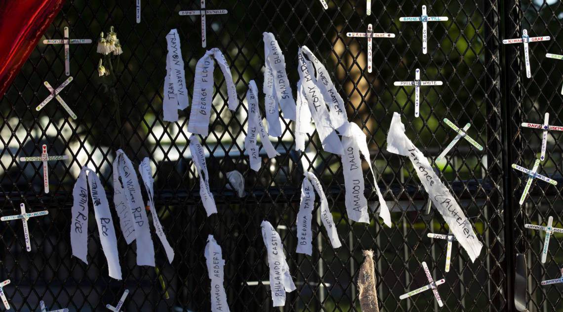 Crosses with the names of people killed by police are hung on a fence at Lafayette Square near the White House, during ongoing protests against police brutality and racism, on June 7, 2020 in Washington, DC. - Demonstrations are being held across the US following the death of George Floyd on May 25, 2020, while being arrested in Minneapolis, Minnesota. (Photo by Jose Luis Magana / AFP)
      Caption