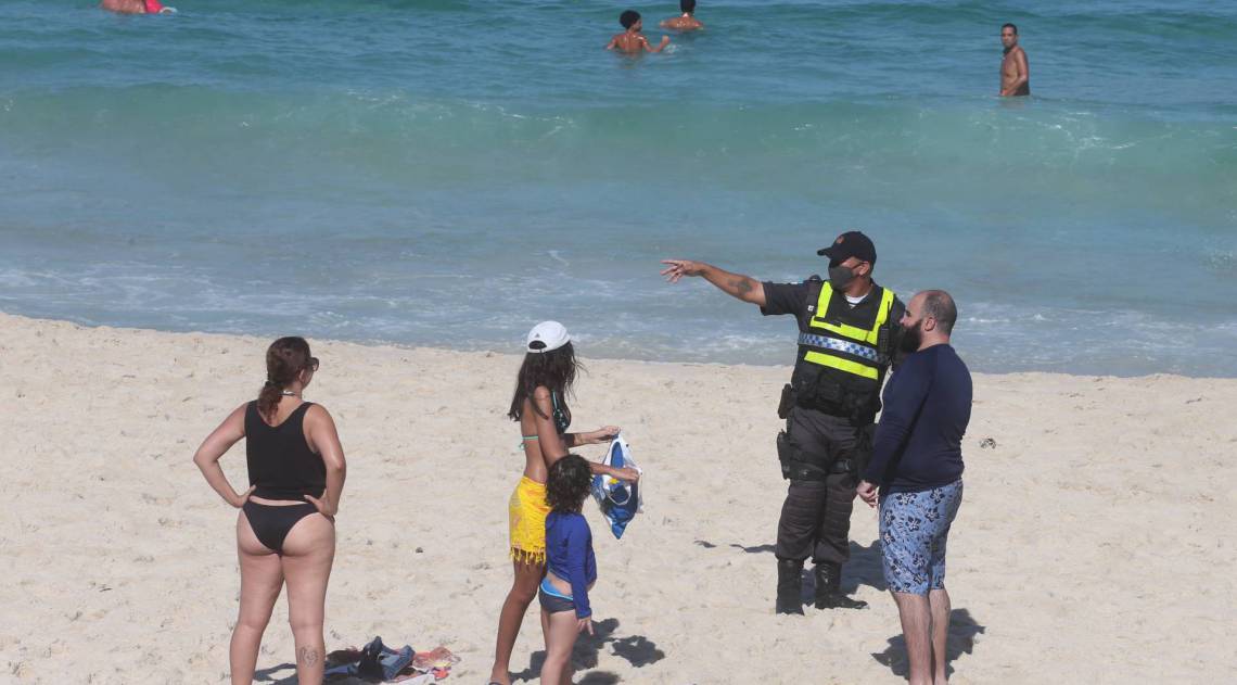 Policial tentar convencer as pessoas a sa&iacute;rem da praia