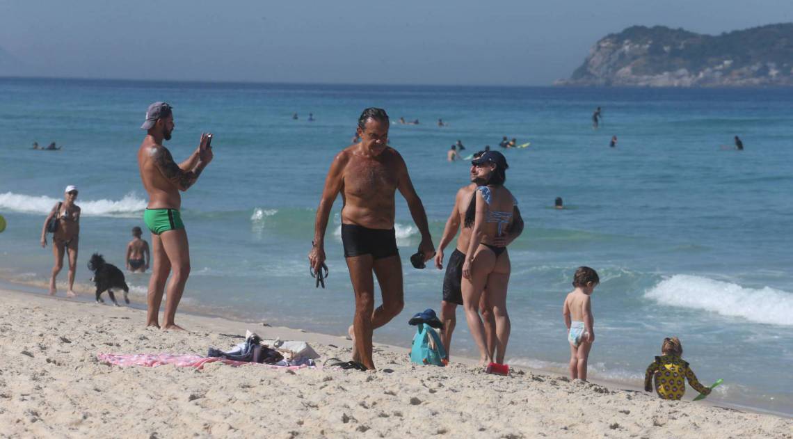 Praia lotada; homem tirando foto de casal