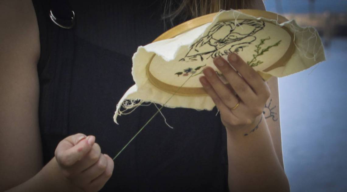 Detalhe do bordado feito pela jornalista Renata Amaral. Fotos dos clientes ganham ares po&eacute;ticos num tecido de algod&atilde;o cru com moldura de bambu