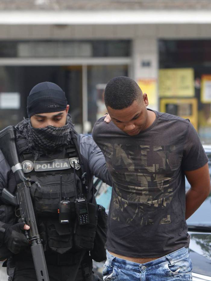 Um dos suspeitos é conduzido pela polícia. Para ampliar território, a milícia passou a explorar transportes