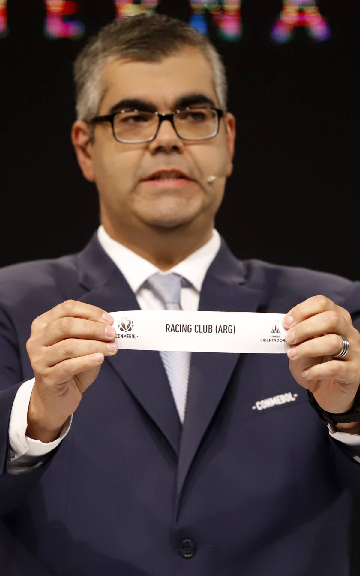 The Clubs Competitions Director of the South American Football Confederation (Conmebol), Frederico Nantes, displays the slip for Argentina's Racing during the draw for the next rounds of the Copa Libertadores and Copa Sudamericana football tournaments at the Conmebol headquarters in Luque, Paraguay, on October 23, 2020. (Photo by Nathalia Aguilar / POOL / AFP)