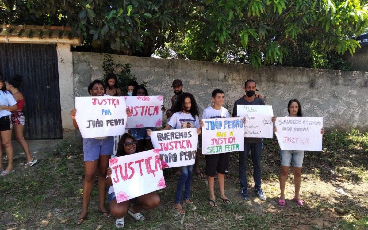 Amigos prestam homenagem ao João Pedro no lado de fora de onde acontece a simulação da morte do menino