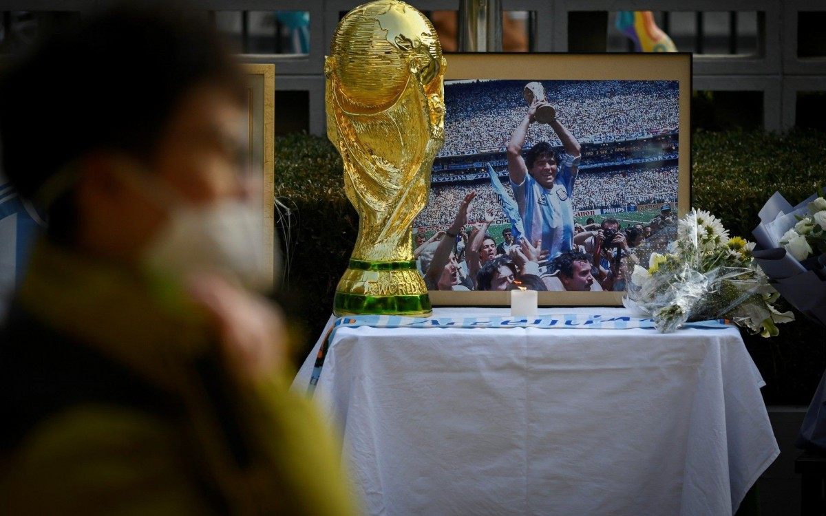 A picture of the late Argentinian football legend Diego Maradona and a model of the FIFA World Cup are displayed at the Argentine embassy in Beijing on November 26, 2020. (Photo by WANG ZHAO / AFP)
      Caption