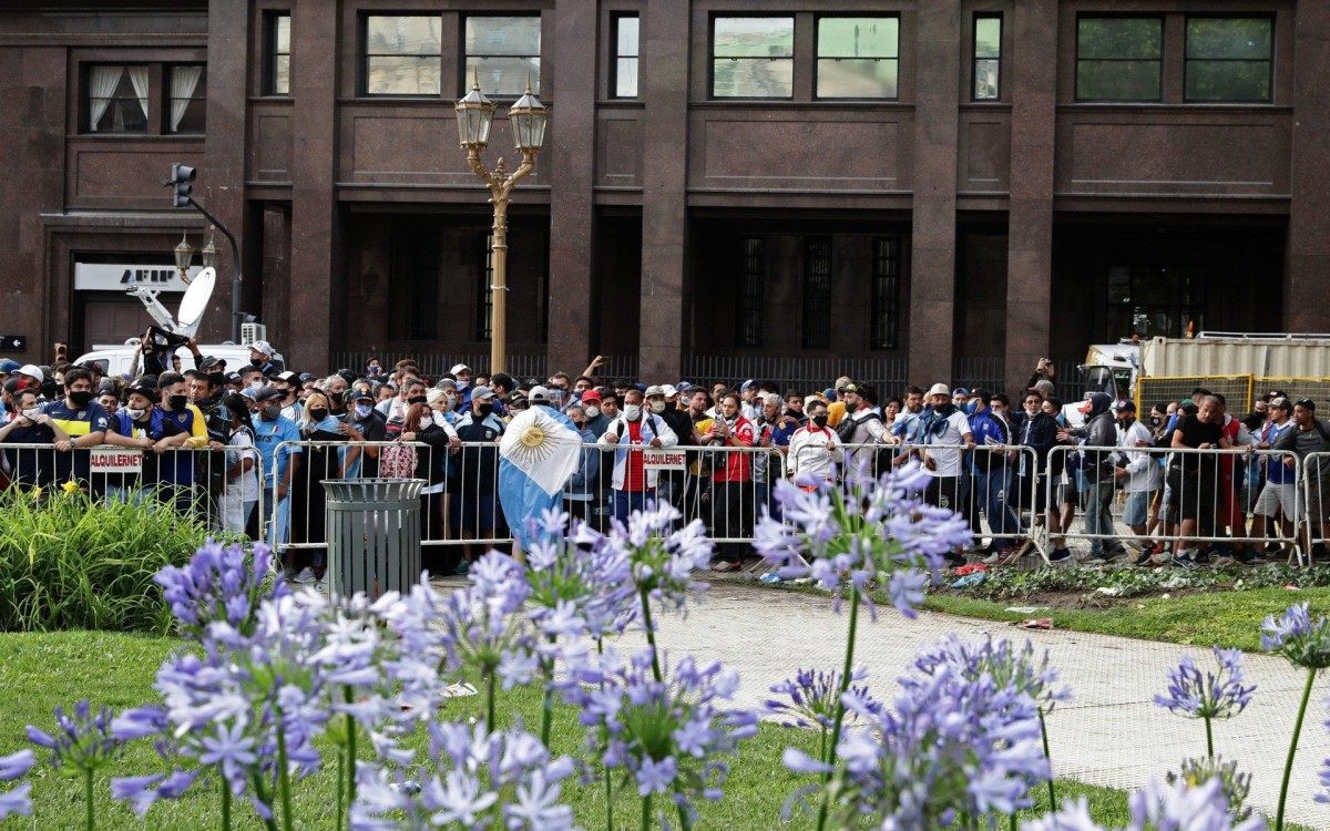 Fans wait to enter the Government House to pay tribute to late football legend Diego Armando Maradona in Buenos Aires, on November 26, 2020. - Diego Maradona's coffin arrived at the presidential palace in Buenos Aires for a period of lying in state, TV reports showed, following the death of the Argentine football legend aged 60 on November 25. Hundreds of people were already lining up to pay their respects to Maradona, who died while recovering from a brain operation, the images from sports channels TyC and ESPN showed. (Photo by ALEJANDRO PAGNI / AFP)
      Caption