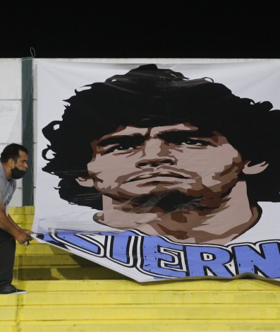 A worker hangs a banner in homage to late Argentine football star Diego Armando Maradona, a day after his passing, before the closed-door Copa Sudamericana round before the quarterfinals football match netween Argentina's Defensa y Justicia and Brazil's Vasco da Gama at the Norberto Tito Tomaghello stadium in Florencio Varela, Buenos Aires, on November 26, 2020. (Photo by Daniel JAYO / various sources / AFP) - AFP