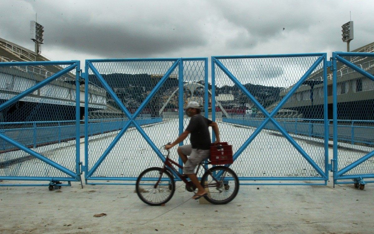 O retrato dos tempos atuais: ciclista de máscara, escudo vital na pandemia, circula em frente ao Sambódromo