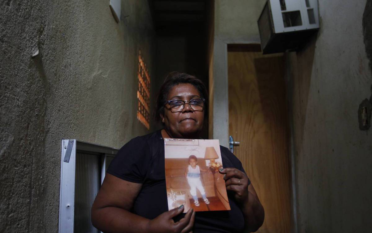 Ang&eacute;lica Guimar&atilde;es segura foto de Marcelo quando crian&ccedil;a. Fam&iacute;lia fez a vida na Gard&ecirc;nia Azul, Jacarepagu&aacute;. - Luciano Belford/Agencia O Dia