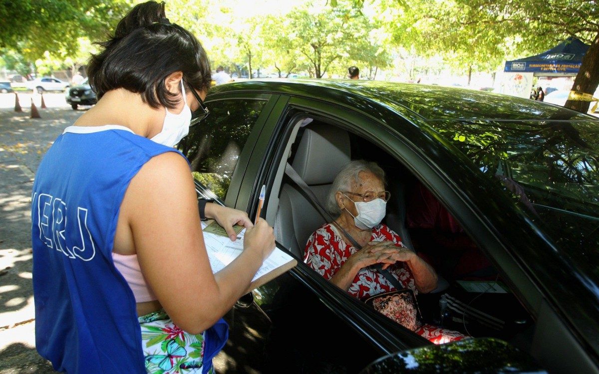Vacina&ccedil;&atilde;o drive - thru, por idade montado no estacionamento no estacionamento da UERJ. Na foto, a senhora Rosilda Linhares e seu neto, Bernardo Linhares.
