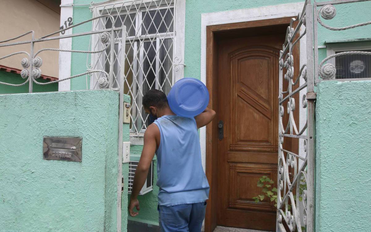 Geral - Populaçao sofre com problemas de abastecimento e qualidade da agua tratada e distribuida pela CEDAE. Na foto, entregador chegando na casa da Sra. Carla Roseira, na Rua Joaquim Martins, no Encantado, zona norte do Rio. - Reginaldo Pimenta / Agencia O Dia