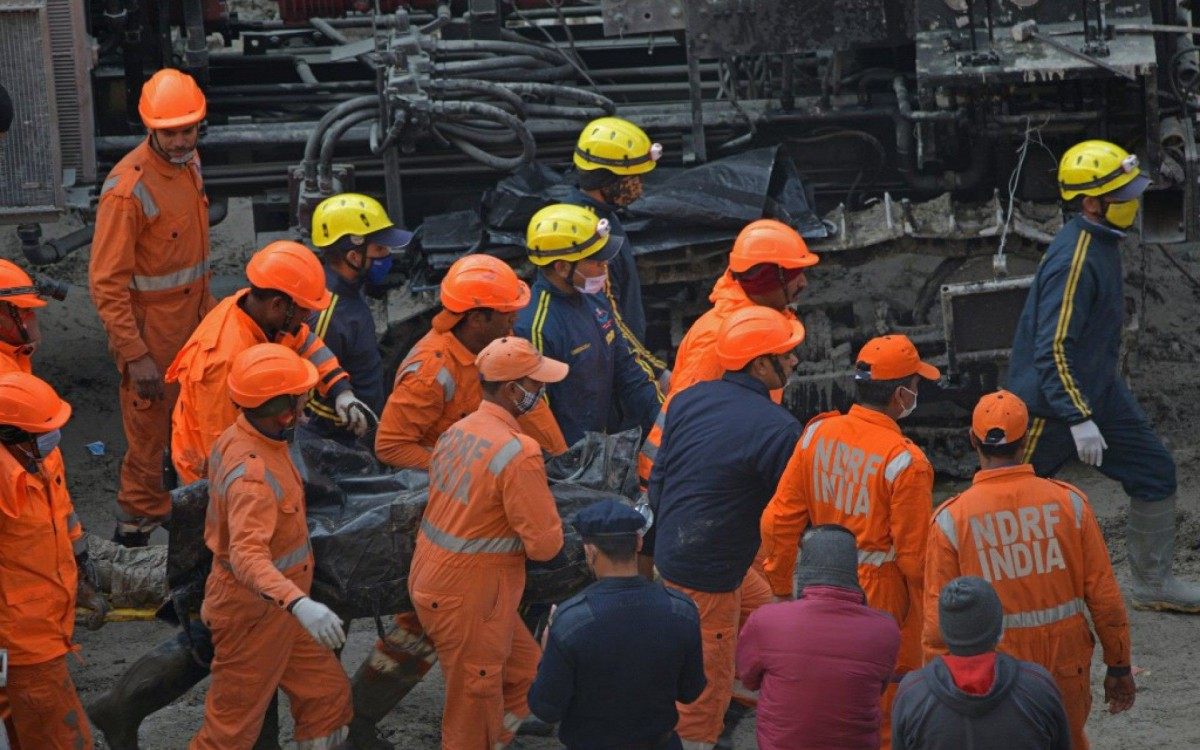 National Disaster Response Force (NDRF) crew carry the body of a victim following rescue efforts from Tapovan tunnel in Chamoli on February 14, 2021, after flash floods thought to have been caused when a glacier broke off on February 7. (Photo by Virender SINGH NEGI / AFP)