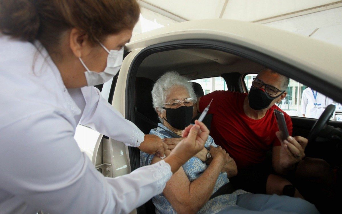 Drive - thru de vacinação no Parque Olímpico, na Barra da Tijuca. na foto, a senhora,Euzi Ferreira, com seu filho Leonardo, observam a profissional que mostra a seringa depois da aplicação.
