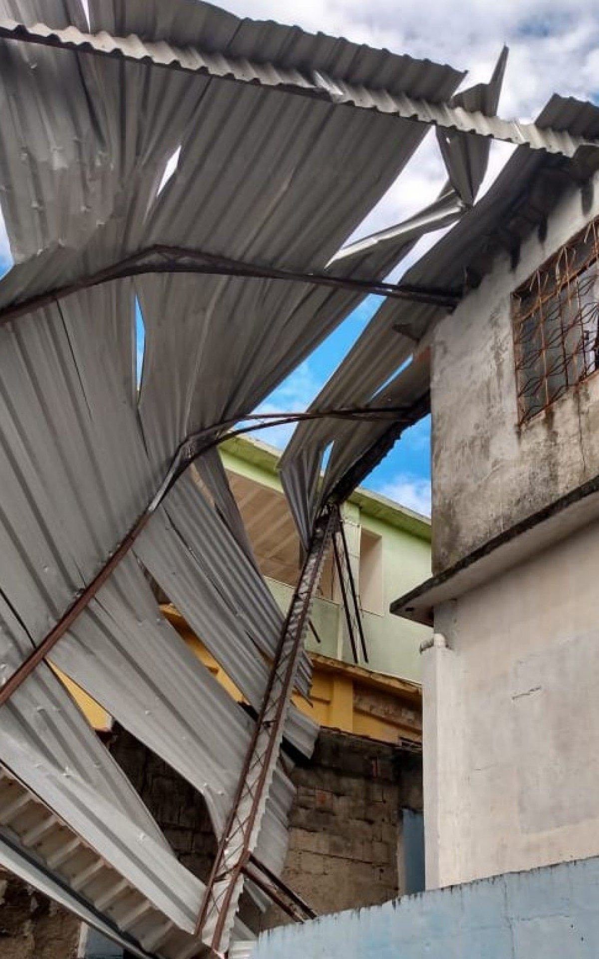 Em Meriti, al&eacute;m das &aacute;rvores, um grande telhado foi arrancado de uma casa, oferecendo risco aos moradores do entorno