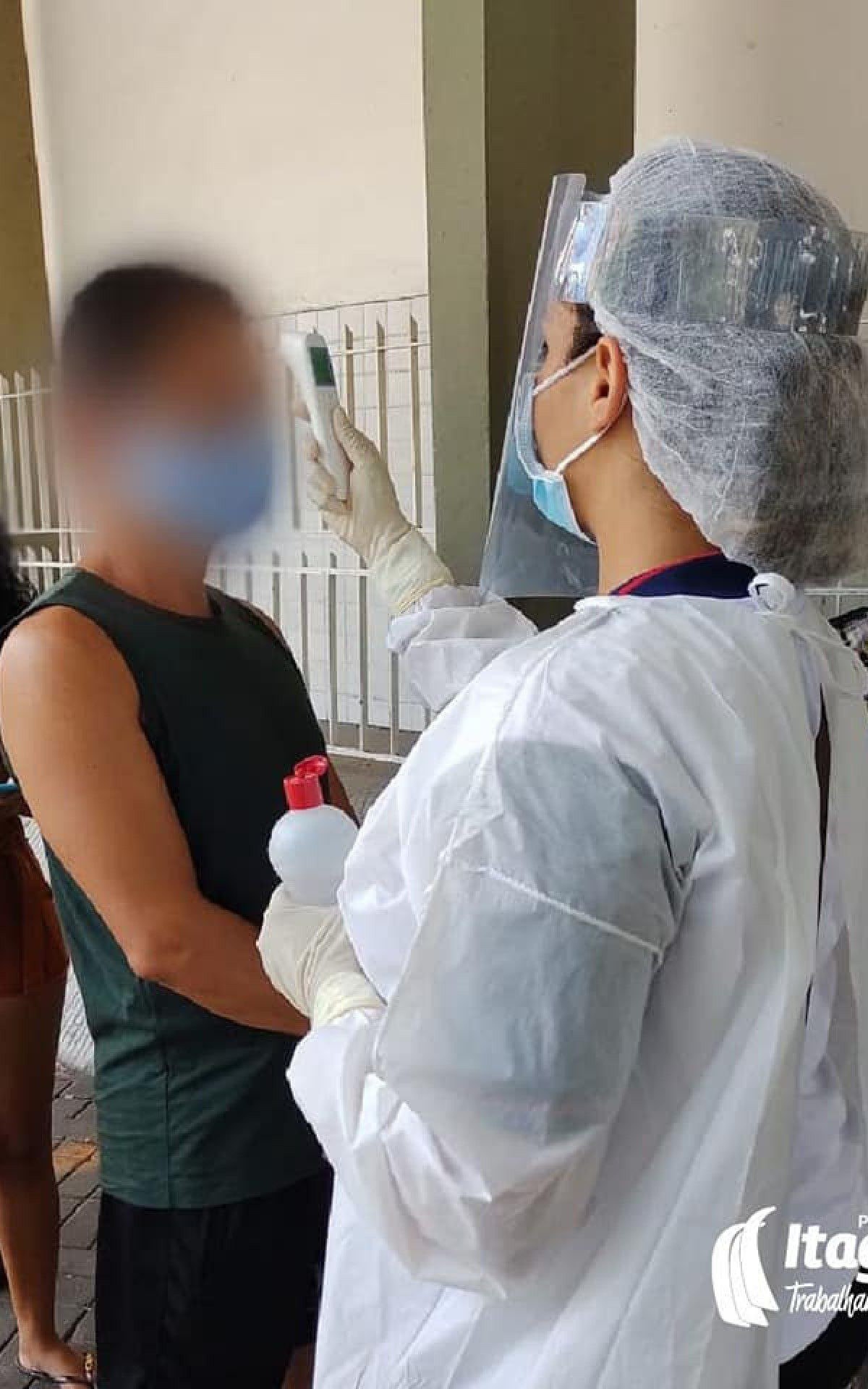 Agente faz medição de temperatura de uma pessoa em uma fila de banco: ação para prevenção