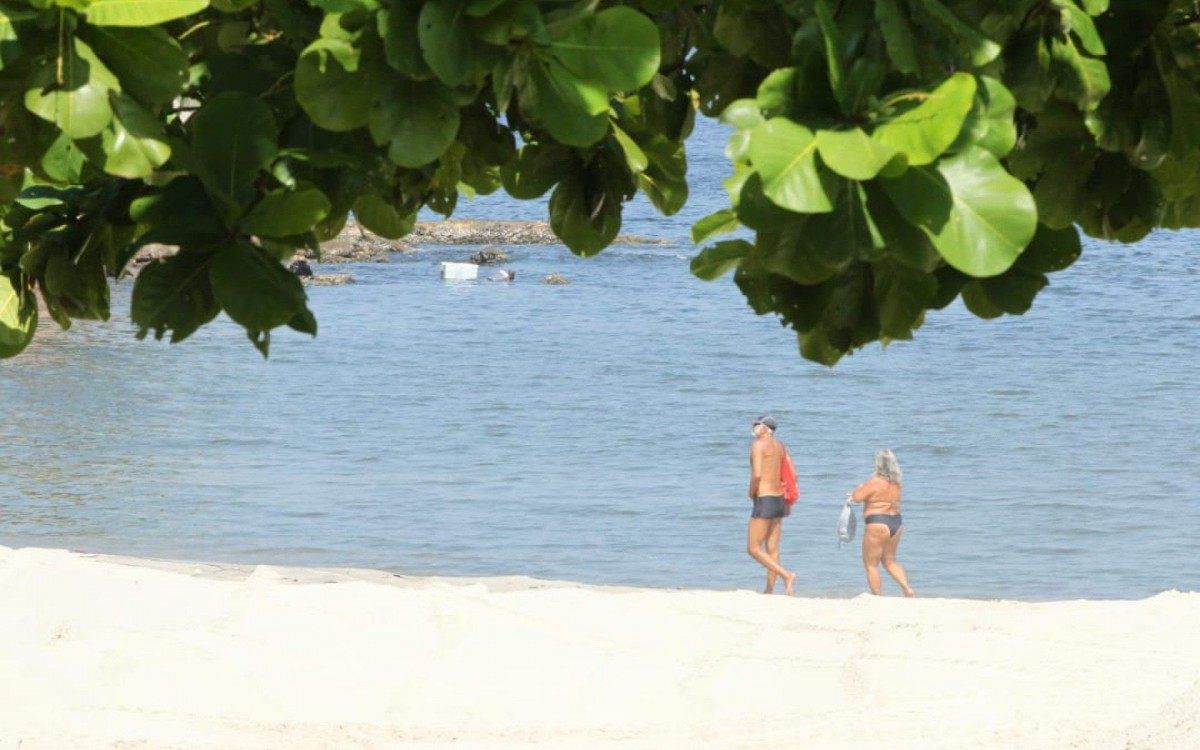 Casal caminha na Praia de Icara&iacute;, em Niter&oacute;i. Perman&ecirc;ncia na areia est&aacute; proibida