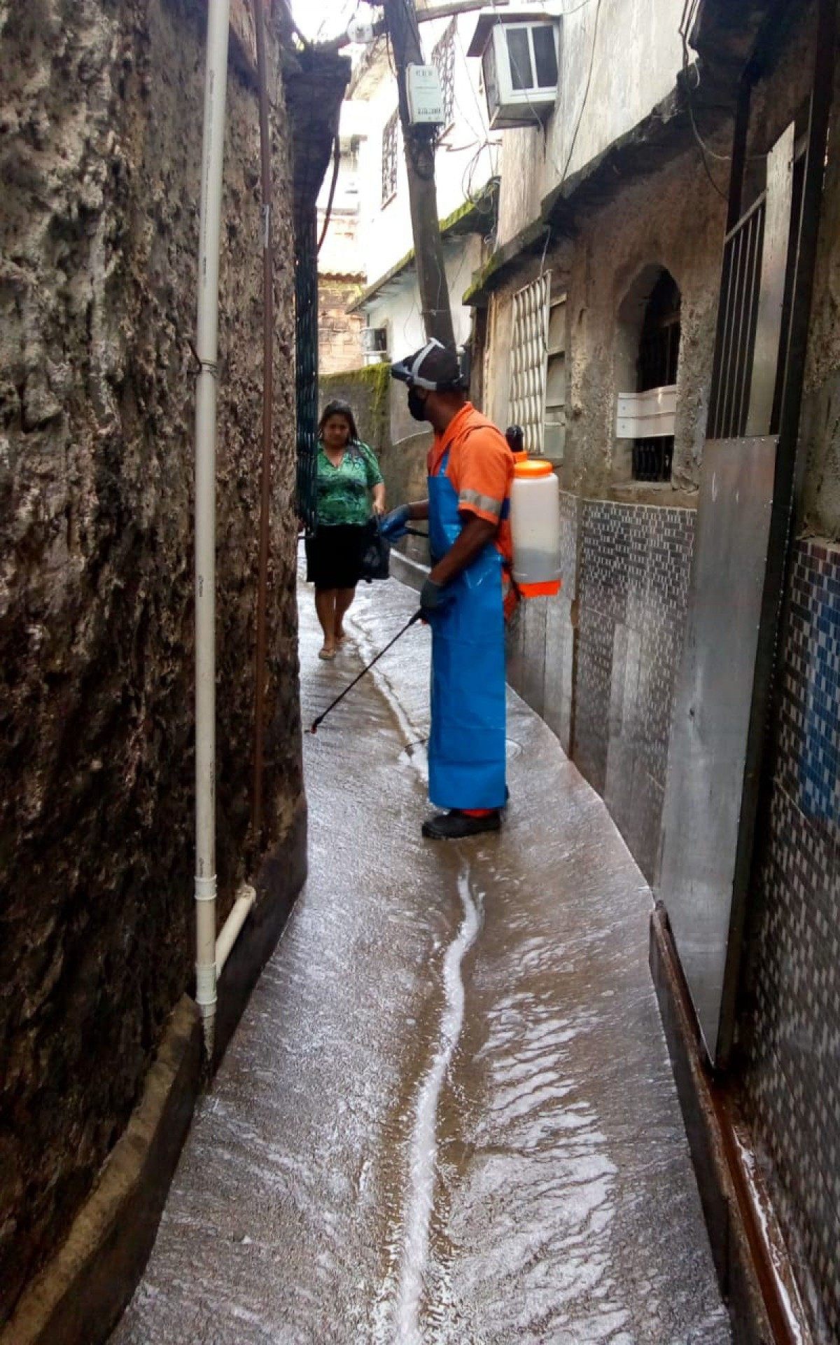 Nas partes mais estreitas das comunidades, garis usam um pulverizador costal
