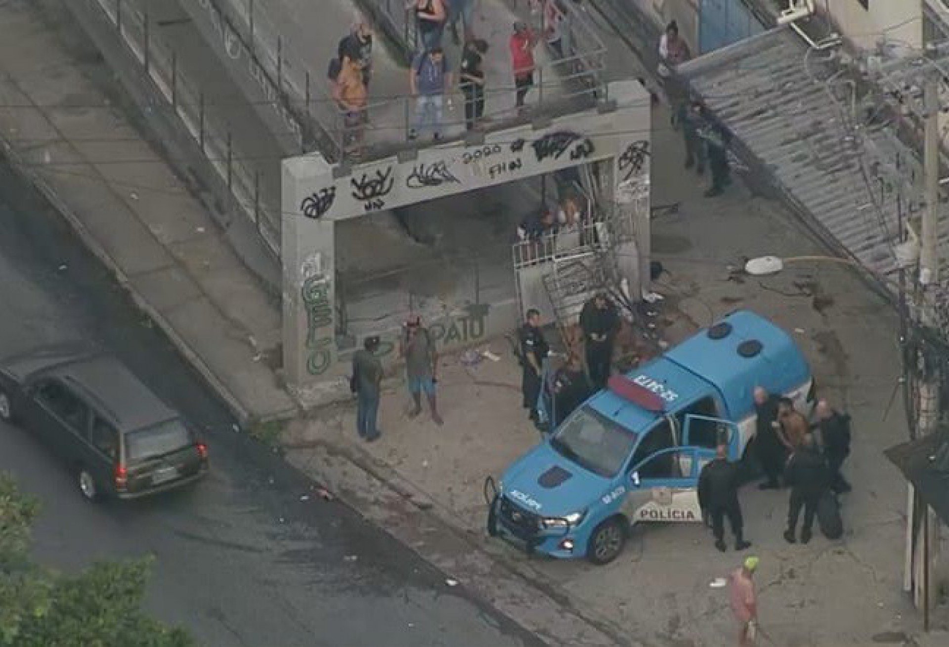 Policiais militares socorrem baleados em passarela da Avenida Martin Luther King, na altura do Morro do Juramento, Zona Norte do Rio - Reprodução/ TV Globo
