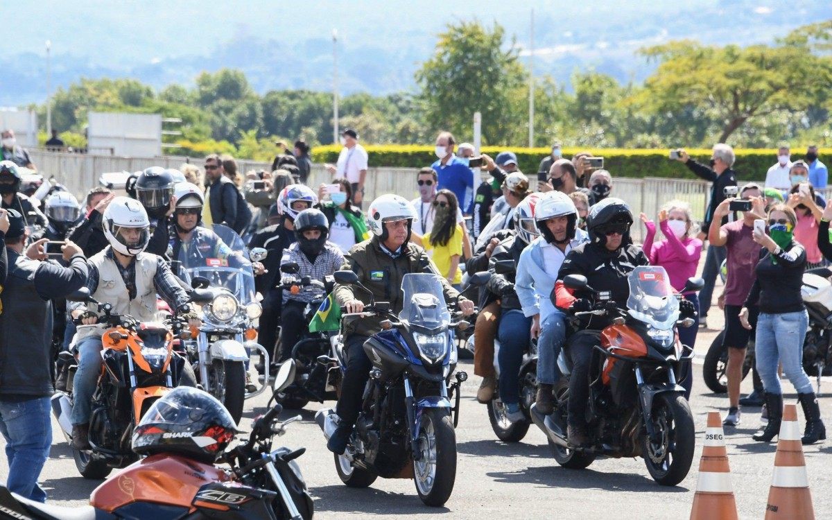 Brazil's President Jair Bolsonaro (C) rides a motorcycle as he leads a caravan of more than 1000 bikers to celebrate Mother's Day in Brasilia on May 9, 2021. (Photo by EVARISTO SA / AFP)
      Caption - AFP