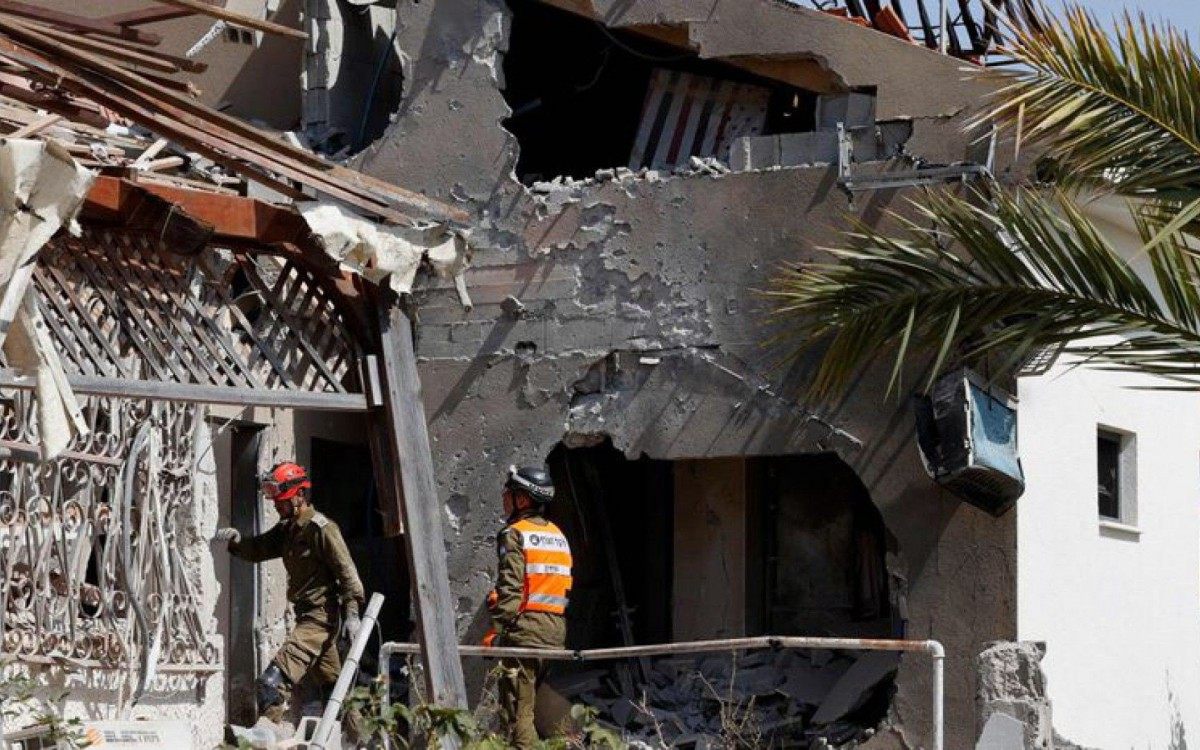 Socorristas numa casa atingida por um foguete lan&ccedil;ado de Gaza, nesta ter&ccedil;a-feira, em Ashkelon (Israel).
