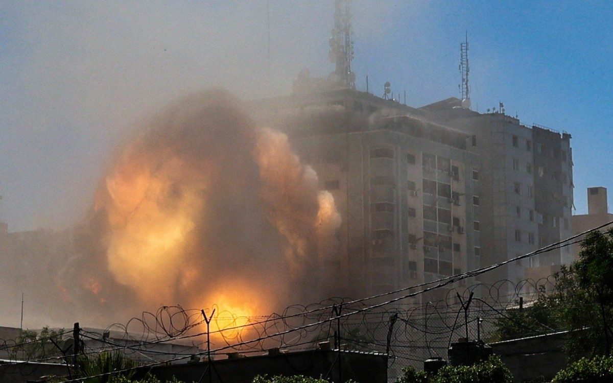 A ball of fire erupts from the Jala Tower as it is destroyed in an Israeli airstrike in Gaza City, controlled by the Palestinian Hamas movement, on May 15, 2021. - Israeli air strikes pounded the Gaza Strip, killing 10 members of an extended family and demolishing a key media building, while Palestinian militants launched rockets in return amid violence in the West Bank. Israel's air force targeted the 13-floor Jala Tower housing Qatar-based Al-Jazeera television and the Associated Press news agency. (Photo by MOHAMMED ABED / AFP)
      Caption