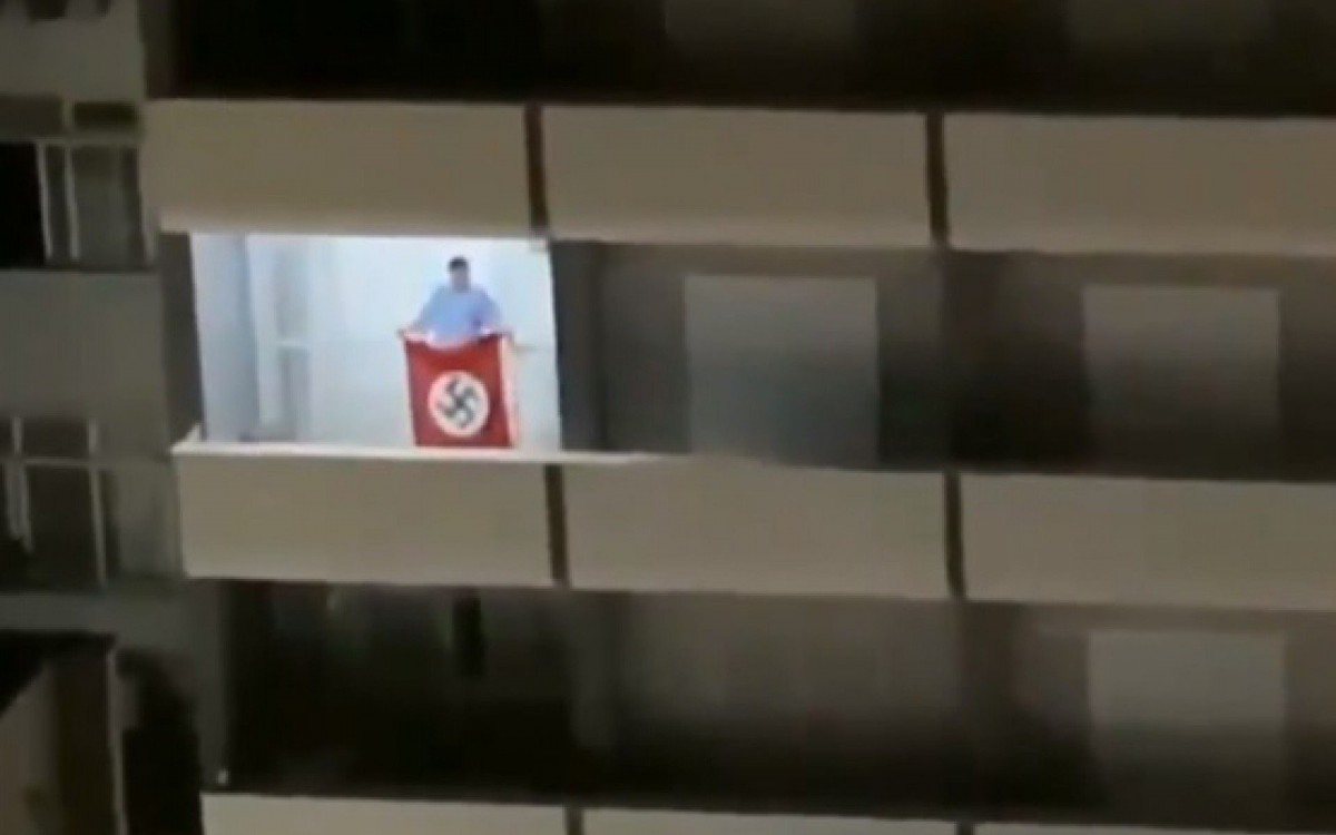 Homem balança uma bandeira nazista na sacada de um apartamento em SC