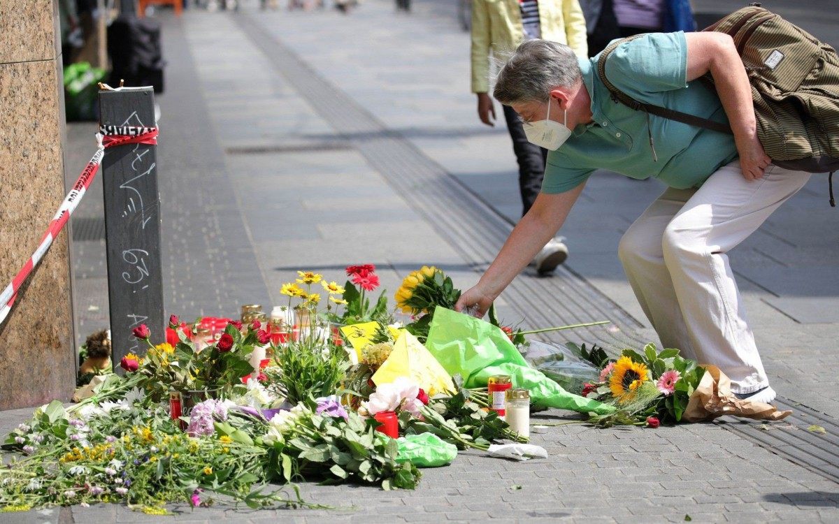 A woman places flowers at a makeshift memorial of flowers and candles in tribute to the victims of a deadly attack in the city center of Wuerzburg, southern Germany, on June 26, 2021. - Investigators were racing to pinpoint the motive of a man who went on a knife rampage in the German city of Wuerzburg, killing three people and leaving five seriously injured. The suspect, a 24-year-old Somali who arrived in Wuerzburg in 2015, staged the attack in the city centre on the evening of Friday, June 25, 2021, striking at a household goods store before advancing to a bank. (Photo by ARMANDO BABANI / AFP)
      Caption