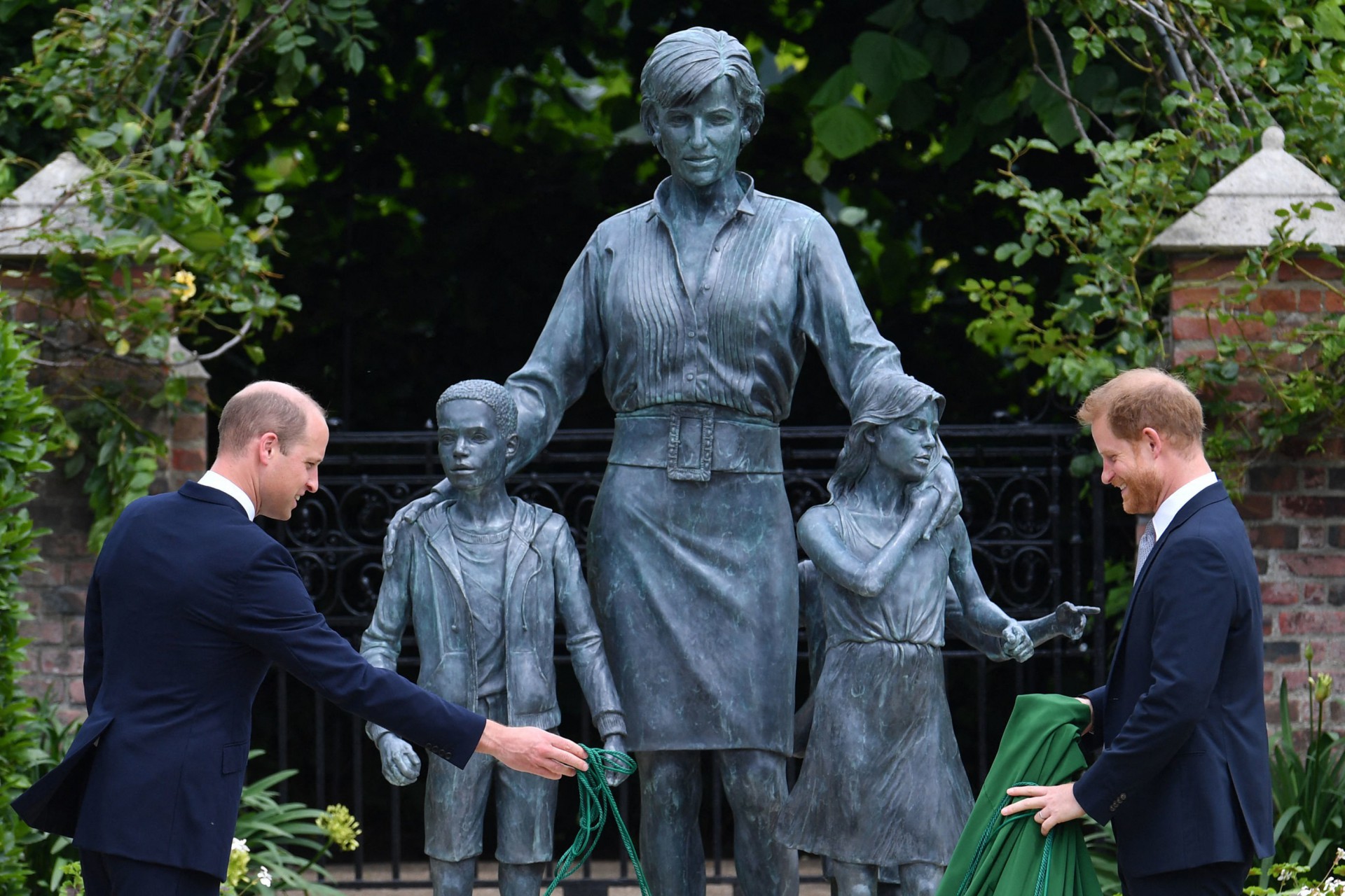 Britain's Prince William, Duke of Cambridge (L) and Britain's Prince Harry, Duke of Sussex unveil a statue of their mother, Princess Diana at The Sunken Garden in Kensington Palace, London on July 1, 2021, which would have been her 60th birthday. - Princes William and Harry set aside their differences on Thursday to unveil a new statue of their mother, Princess Diana, on what would have been her 60th birthday. (Photo by Dominic Lipinski / POOL / AFP) - AFP