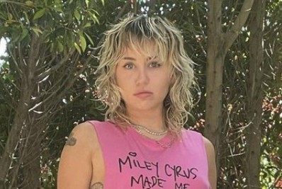 Miley Cyrus aparece só de camiseta em cima do capô do carro do pai