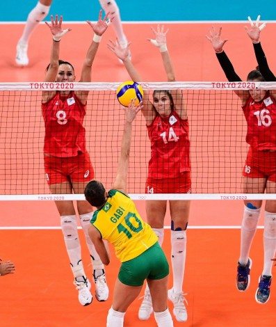 Brazil's Gabriela Braga Guimaraes hits the ball in front of (L-R) Russia's Nataliya Goncharova, Irina Fetisova and Irina Voronkova in the women's quarter-final volleyball match between Brazil and Russia during the Tokyo 2020 Olympic Games at Ariake Arena in Tokyo on August 4, 2021. (Photo by PEDRO PARDO / AFP)