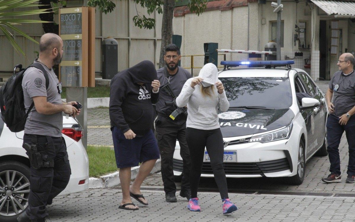 Polícia prende 15 em operação contra a milícia; bando lavava dinheiro até com criptomoedas, na foto o casal Luiz Carlos Principe Jr e Clébia Barros Gondim, presos chegando na Cidade da Policia (cidpol),nesta quinta feira (23). - Marcos Porto/Agencia O Dia