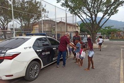 Policial distribui doces de São Cosme e São Damião a crianças, em Guapimirim